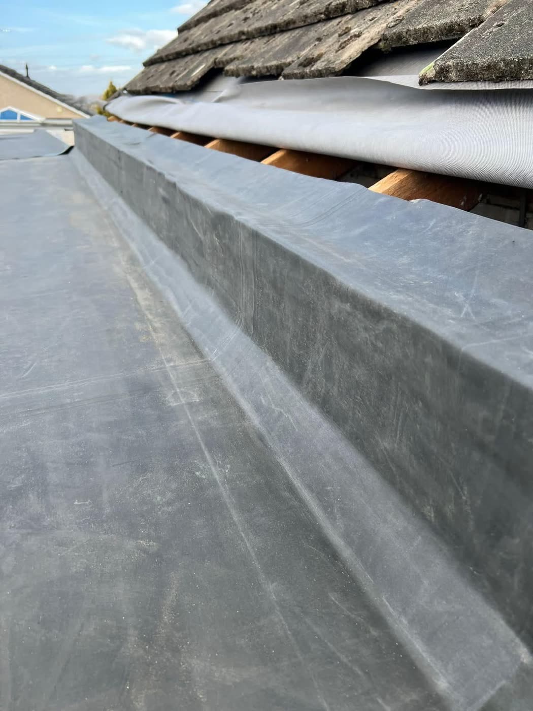 EPDM rubber roof upstand detail beside a tiled roof